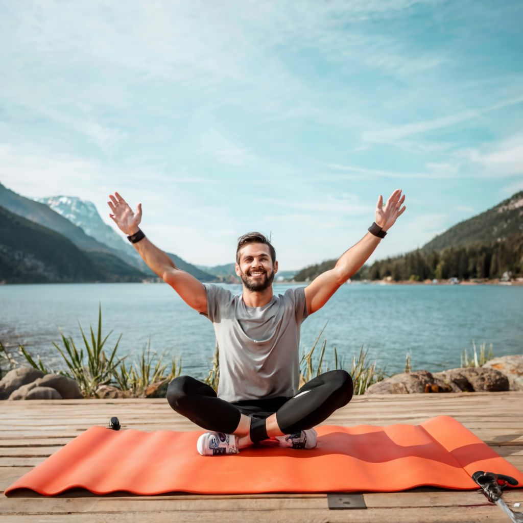 homme au bord d'un lac avec son tapis de sport